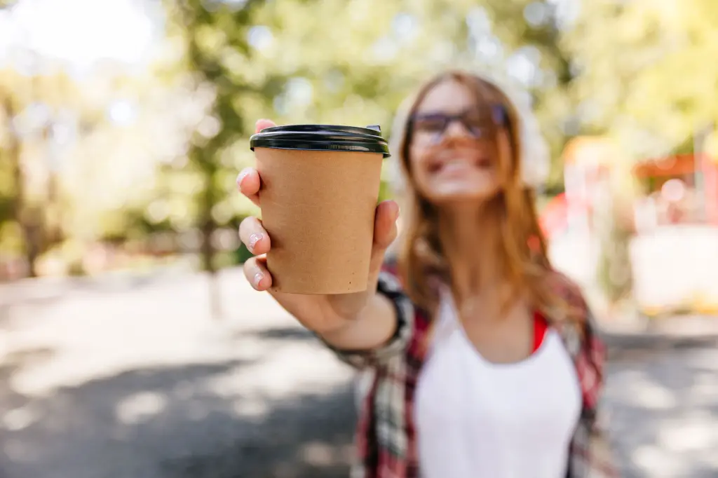 blur-portrait-adorable-woman-holding-cup-coffee-carefree-stylish-girl-enjoying-summer-day.webp